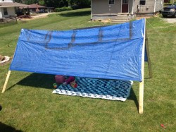 Make your own tent with a tarp and scrap wood.